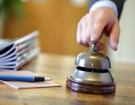 Person ringing a silver concierge bell 